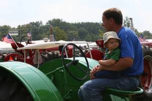 The look on this baby's face is so precious. And so is the loving way the child is held by his/her father, who is awaiting his spot in the tractor parade.
