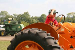 One can only imagine the thoughts fleeting through this boy's mind as he sits behind the wheel of this Co-op (I think) tractor.