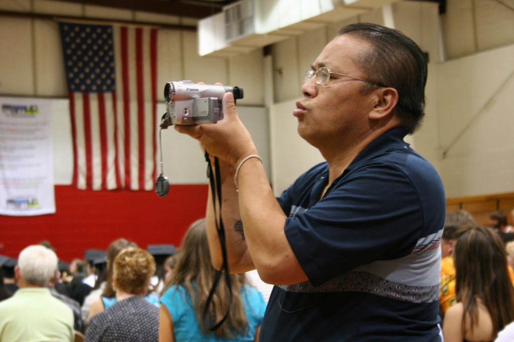 Hmong man videotaping graduation ceremony