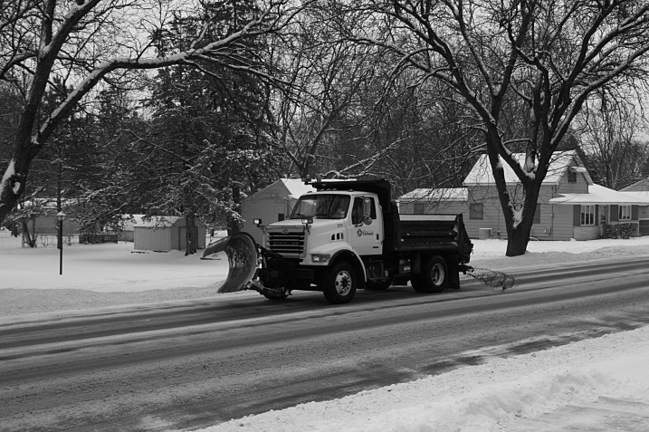 A city of Faribault snow plow spreading salt and sand onto the street past my house on Monday.