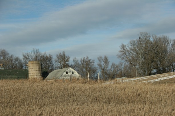 Farms, white barn behind hill