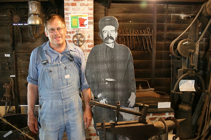 Blacksmith shop, John with photo of Frank