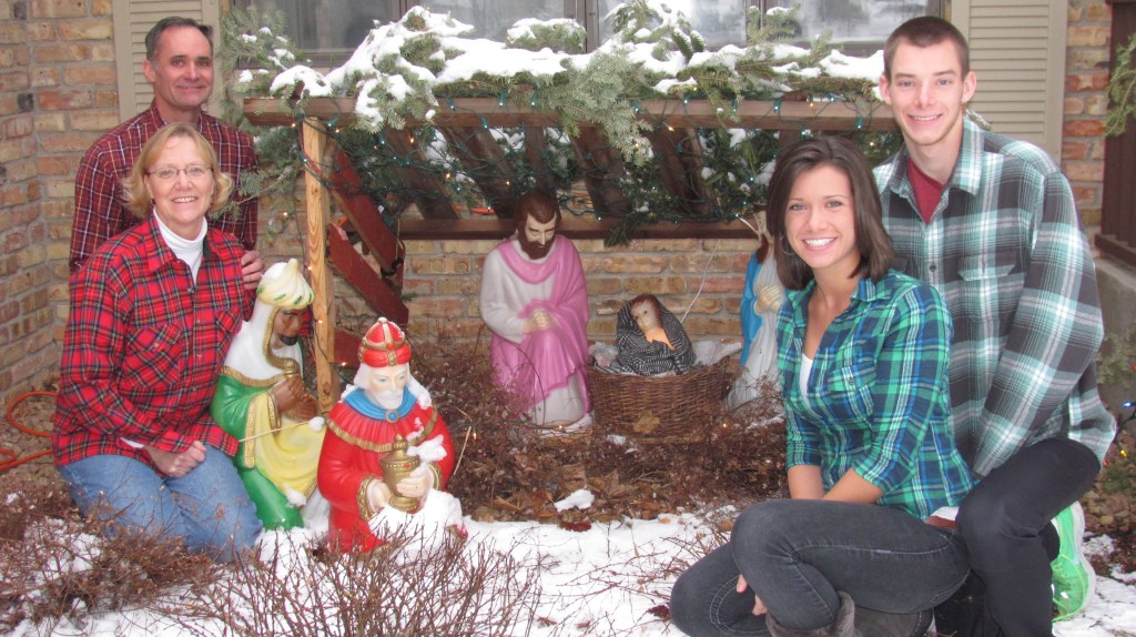 Patrick Mader with his wife, Karen, and children, Karl and Ellen, by the family's nativity set. the wood stable was crafted of wood from the barn on the childhood farm (home of his parents, George and Mary Margaret Mader) near St. Bonifacius where Mader grew up.