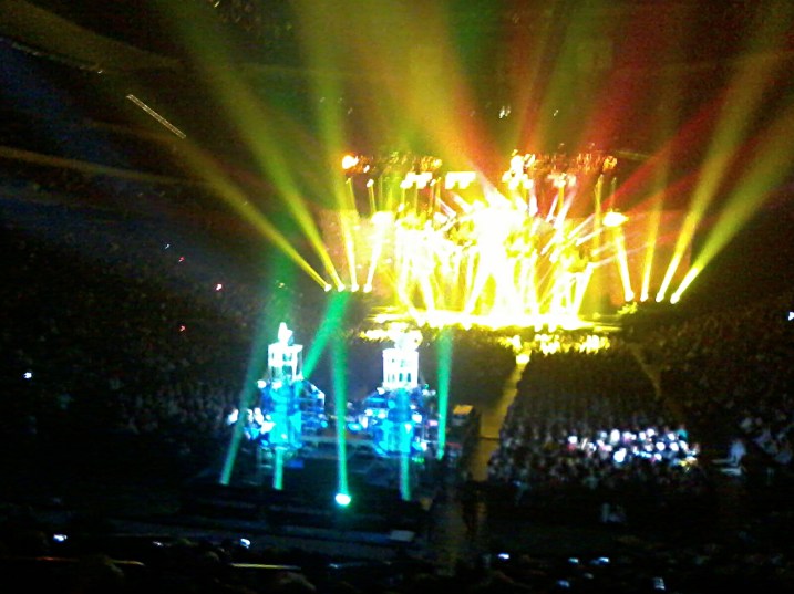 A view of the stage in the background and performers in the foreground elevated onto tiny platforms. I apologize for the horrible images, but DSLR cameras are not allowed into a concert venue and I don't own a compact camera. This image and the second were taken with my cell phone.