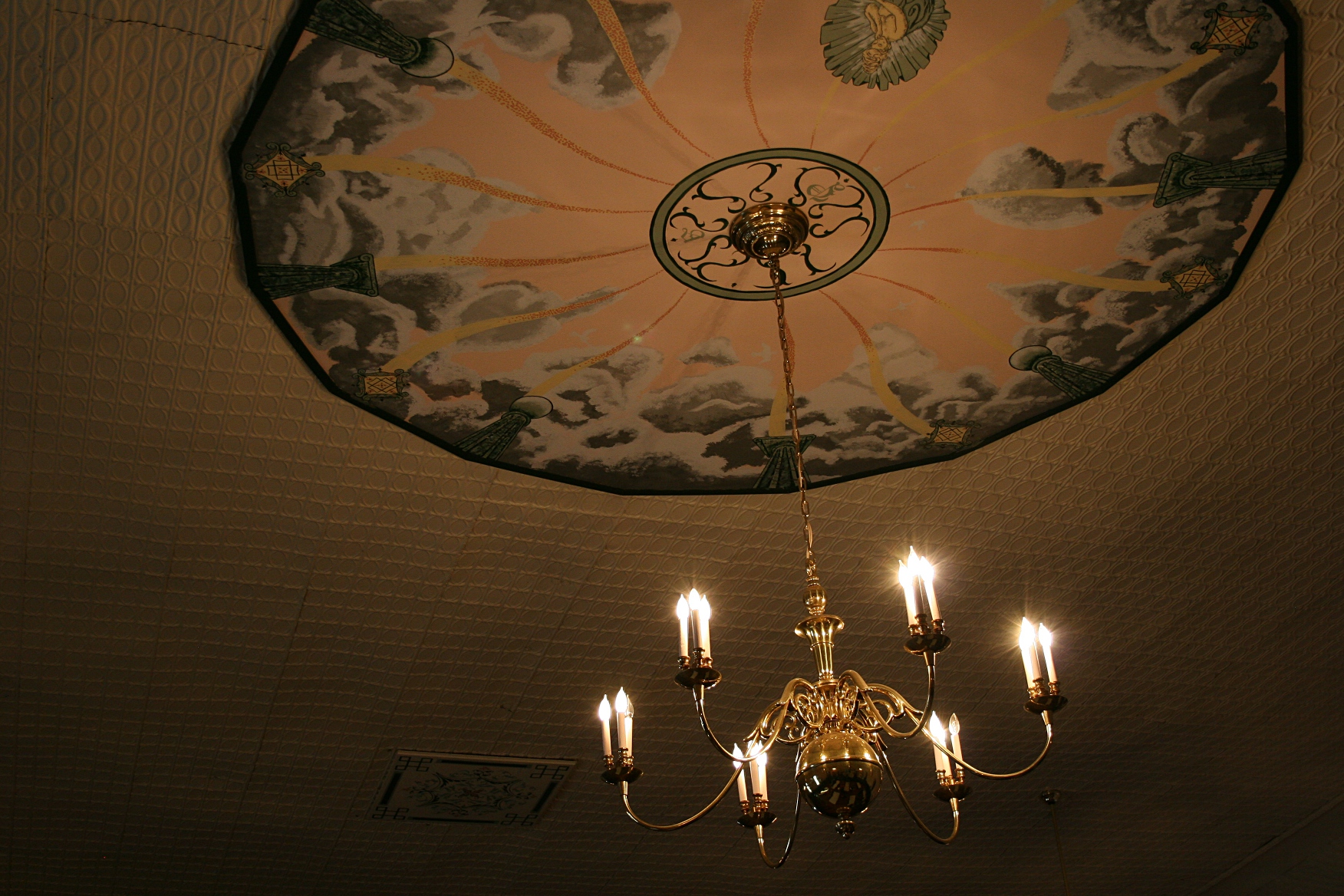 The ceiling plaster had crumbled, so an artist laid on his back to re-create this mural on sheetrock in the center of the performance space.