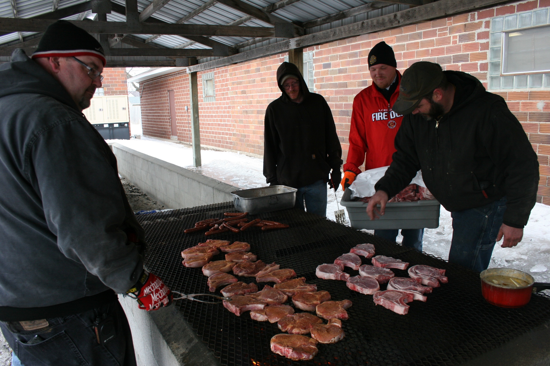 Volunteer firefighters, including my cousin Randy, left, grill pork chops outside the hall.