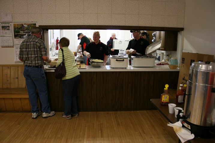 Harlan and Karen step up to the serving window, where Erin, center, and other volunteers dish up food.