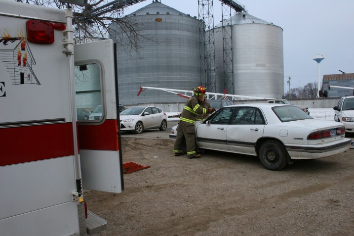 Volunteer firemen remove the windshield from a junk car.