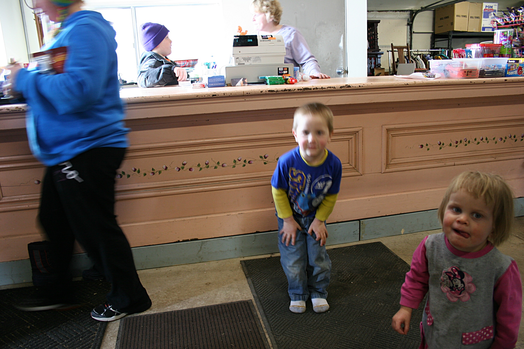 A young customer exits The Store, left, while three of the Thooft kids, including Maxwell, 4, and Beatrice, 21 months, hang out with Mom.