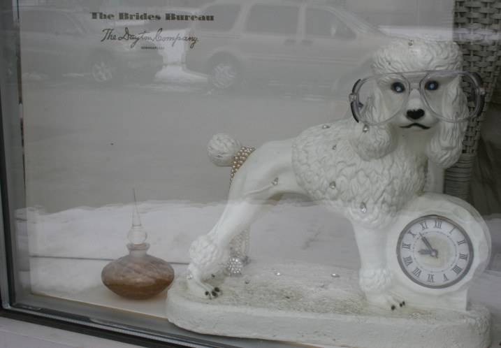 A kitschy poodle clock in a window display.