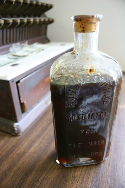 An aged bottle of "auxiliator for the hair."