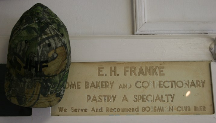 Hooks for caps hang by the vintage signs.