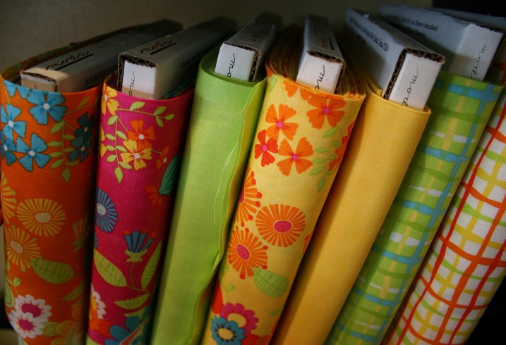 Bolts of eye-catching fabrics in bright hues line shelves.