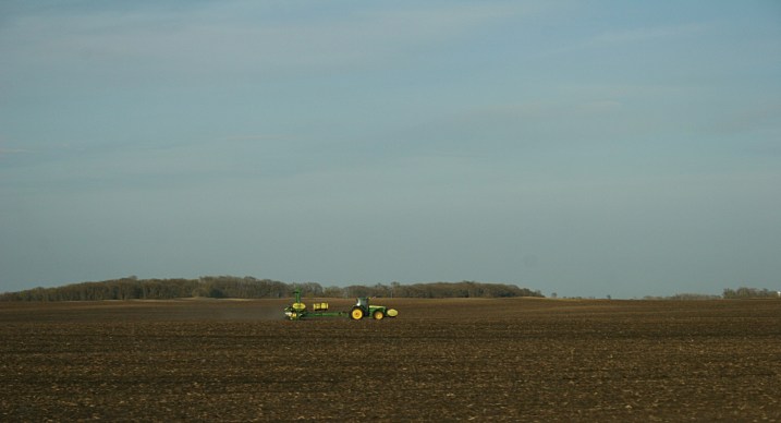 As the sun begins to set along Minnesota Highway 15, a John Deere works the land.