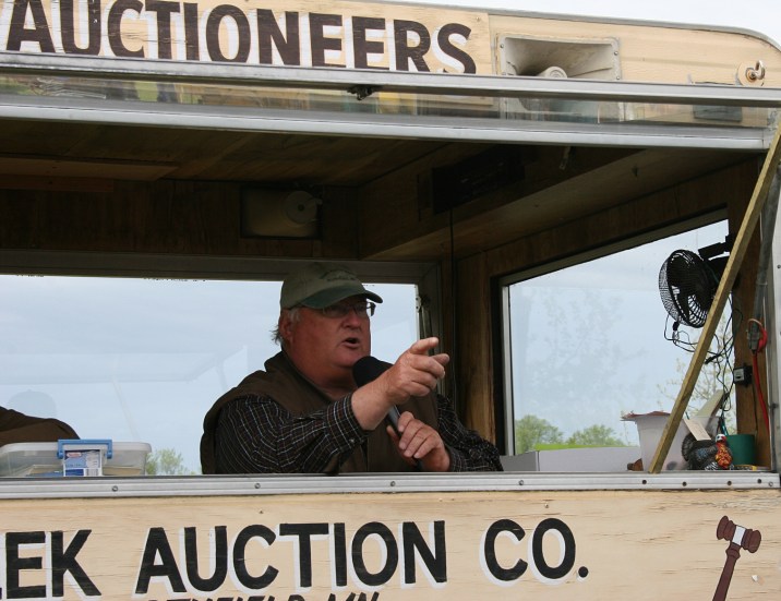 The auctioneer solicits bids from his movable auction wagon.