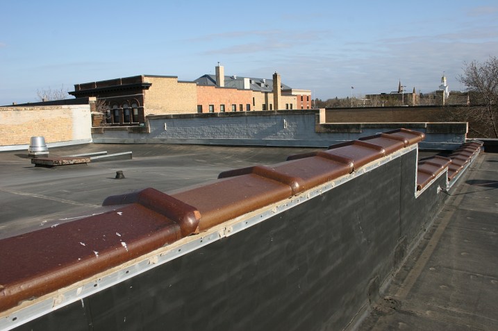 On the left, a low wall separates the printing business rooftop from the theatre roof.
