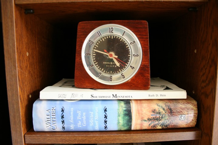 Inside one of the cubbies in the entertainment center, I arranged these books, purchased at an annual used book sale and Faribault, and this alarm clock, bought at the Faribault Salvation Army.