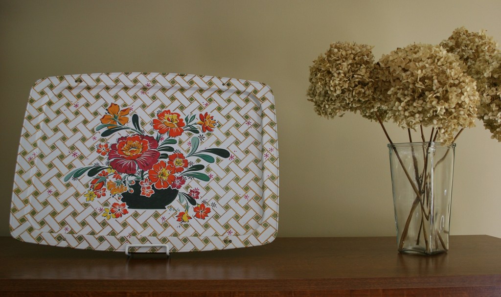 Another TV tray, repurposed as art, sits atop the entertainment center in my living room along with dried hydrangea from a bush outside my front door.