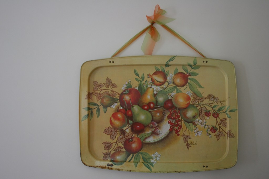 I removed the folding legs from this TV tray, attached a ribbon and hung it in my dining room. I have several more of these same trays, purchased at a yard sale.