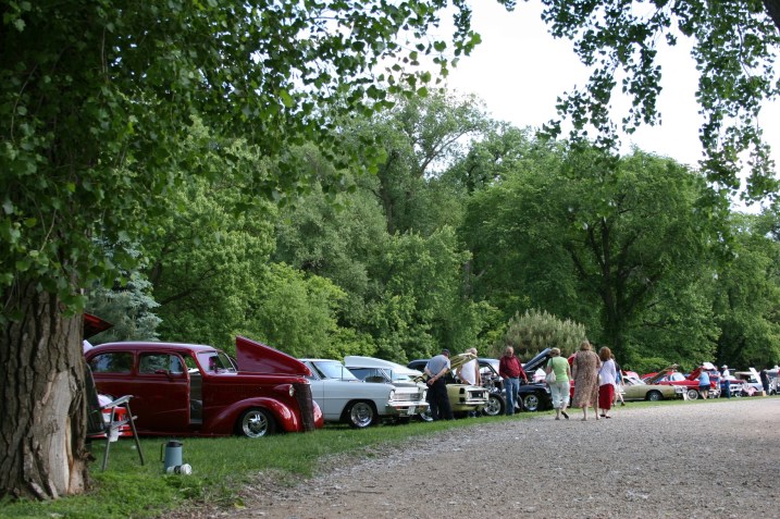 Vintage vehicles line the grassy banks of the Straight River in TeePee Tonka Park, Faribault.