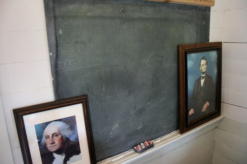 Presidential portraits grace the blackboard by the teacher's desk.