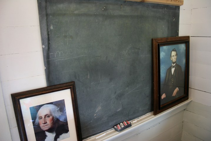 Presidential portraits grace the blackboard by the teacher's desk.
