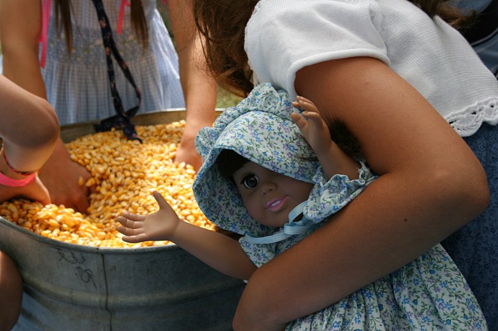 My niece keeps a tight grip on her Laura doll while sifting through corn.