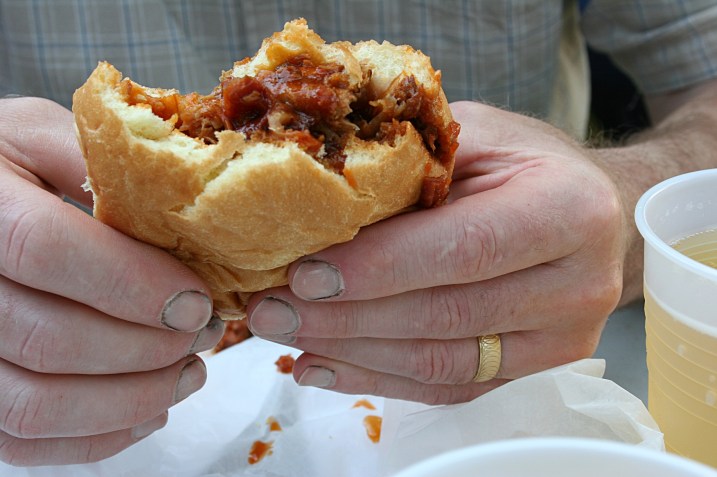 Enjoying a pork sandwich and a beer.