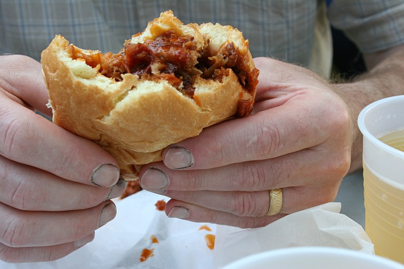 Enjoying a pork sandwich and a beer.