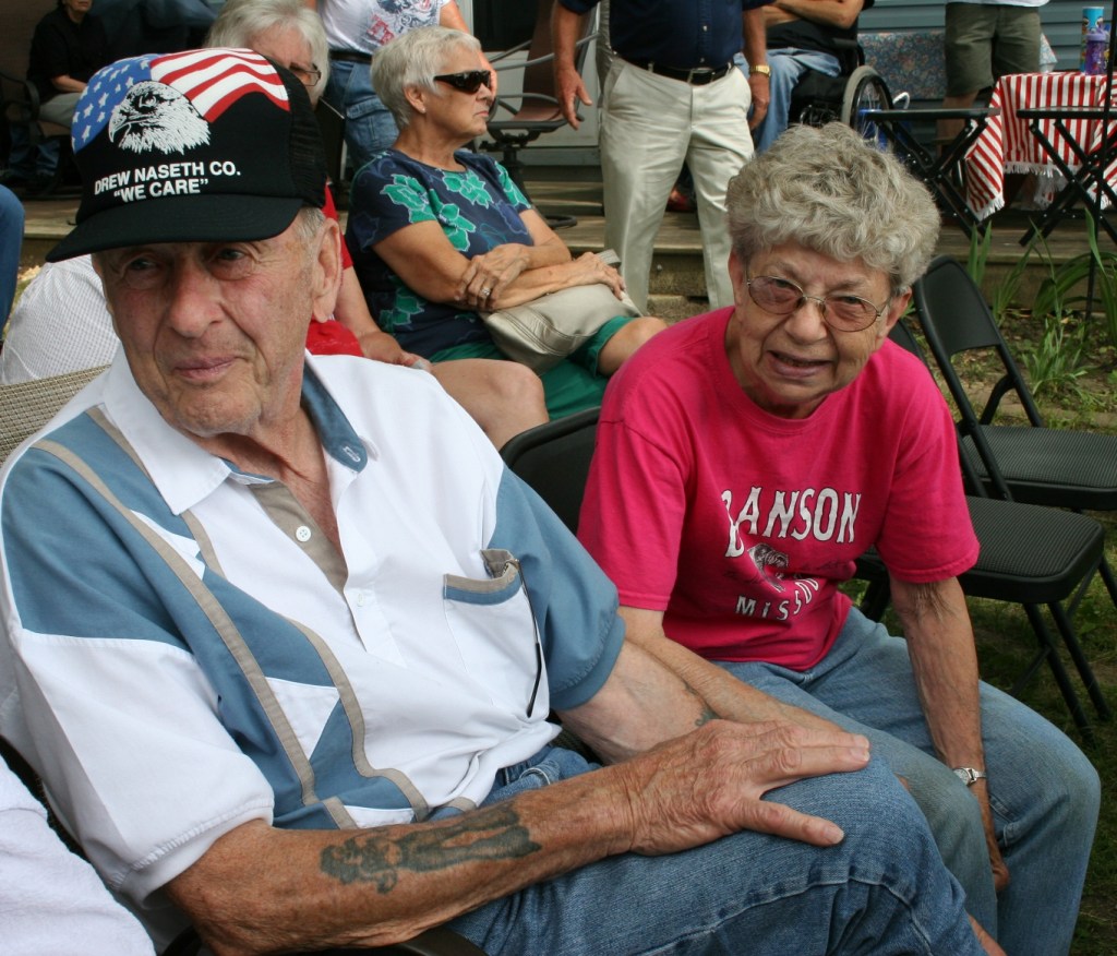 Geri Larson with her friend, George LaRoche, who installed the poles for the military flags on her property.
