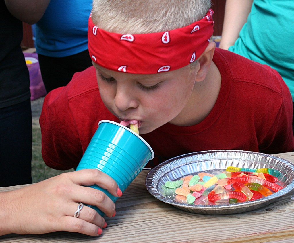 Dropping gummy worms into a cup.