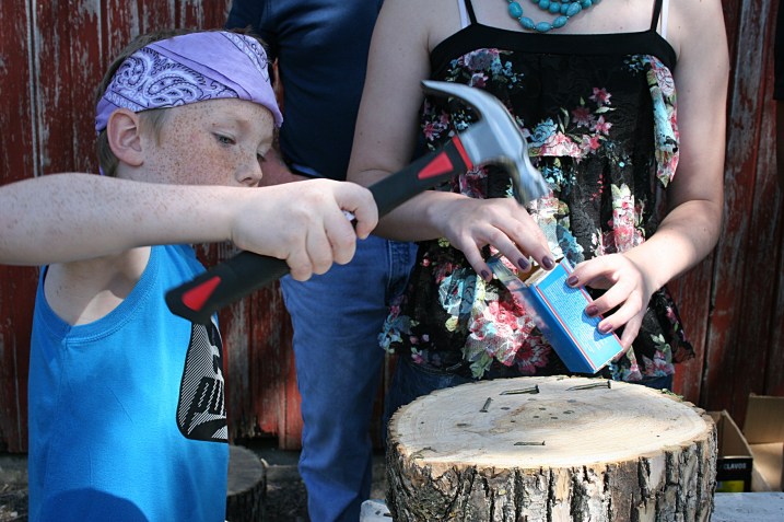 Big sister assists little brother in the kids' nail driving contest.