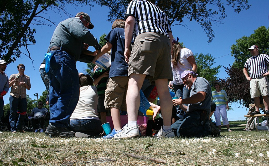 Referees watch over the competition in which contestants filled cups, attached to their feet, with popcorn and raced to fill ice cream buckets.