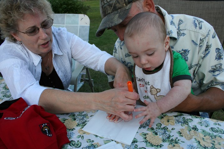 Grandma Cheryl and Grandpa Roger help 6-month-old Aston make a luminary.