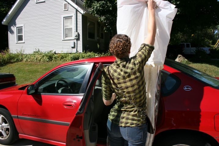 Miranda carefully lifts the beaded replica vintage bridal gown for placement inside her car.