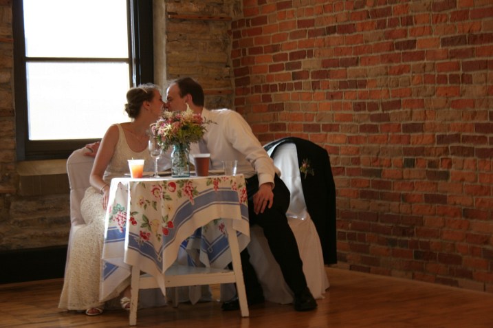 A sweet kiss at their wedding reception sweetheart table set just for them.