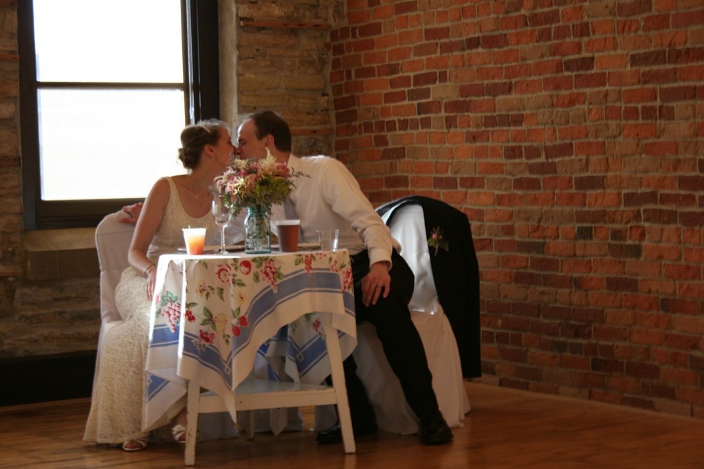 A sweet kiss at their wedding reception sweetheart table set just for them.
