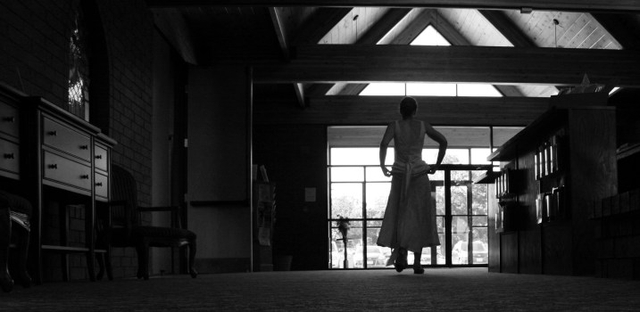 The bride lifts up her dress as she walks through the narthex.