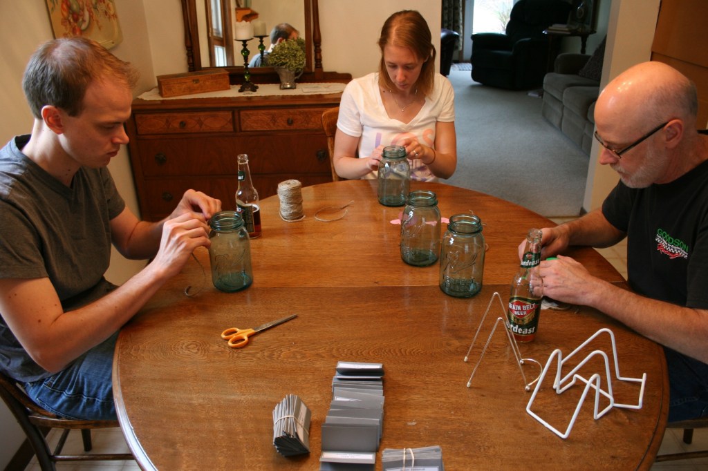 The bridal couple and the father-of-the-bride worked on table numbers for the vintage blue canning jars that would grace tables at the reception. The choice of these jars followed the vintage theme and the color scheme for the wedding.