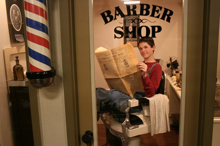 Noah, who volunteers at the library through its youth program, sat in the museum's barbershop chair during A Night at the Museum. in the museum barbershop.