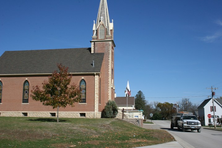 Another truck and horse trailer pass by the old Catholic church.