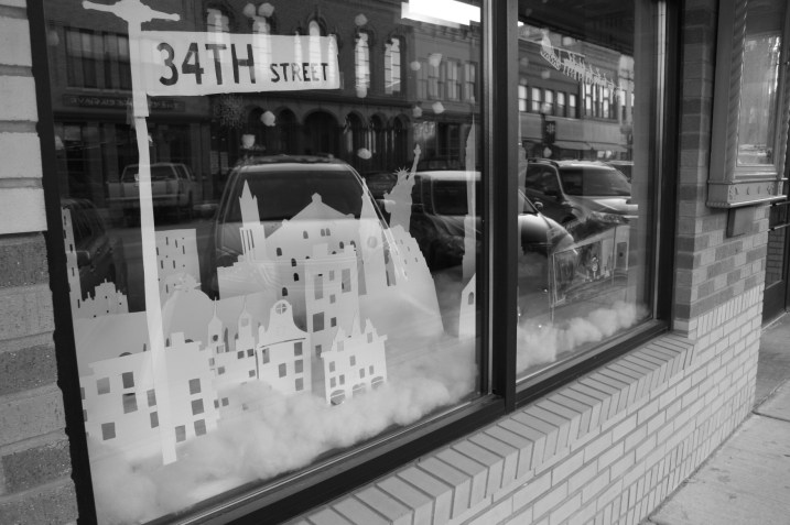 An artistic interpretation of Miracle on 34th Street graces a front window at the Paradise Center for the Arts, which reflects some of downtown Faribault's historic buildings.