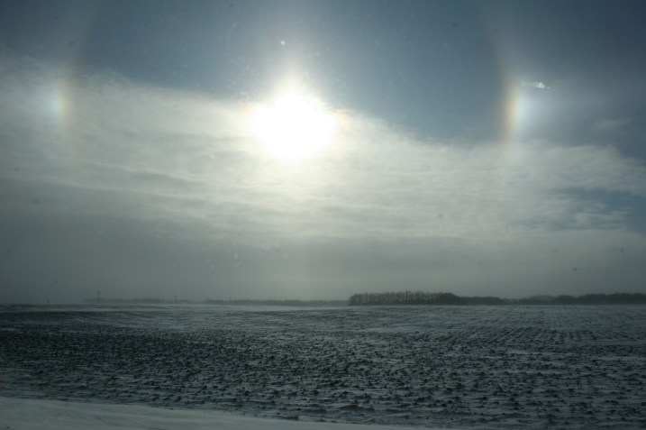 Sun dogs photographed through the dirty passenger side window of the van this morning east of Lamberton along U.S. Highway 14.