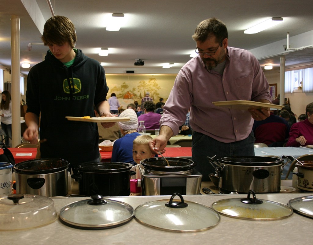 Diners spoon chili into cups.