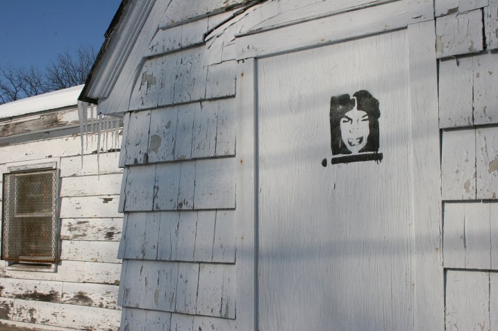 Why is this face painted on a door of the building where the tow truck is parked? And whose face is this?