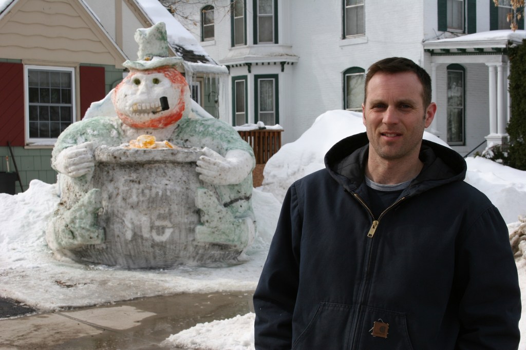 Faribault resident Kurt Klett and his latest snow sculpture, a leprechaun with a pot of gold.