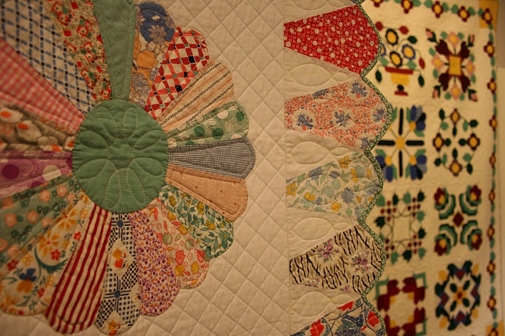 A close-up of the traditional Dresden Plate pattern in the foreground with a second quilt in the background.
