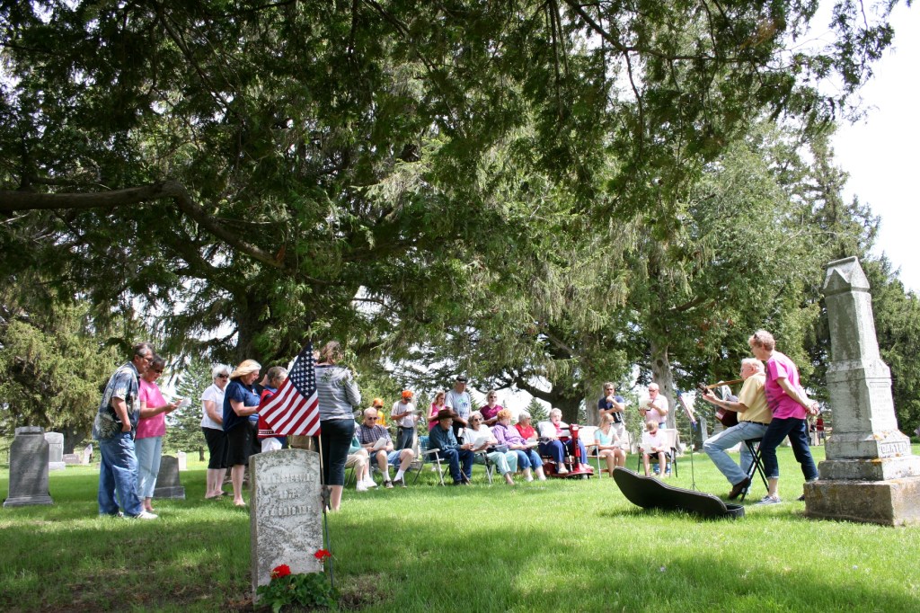 Between the tombstones, below the flag...