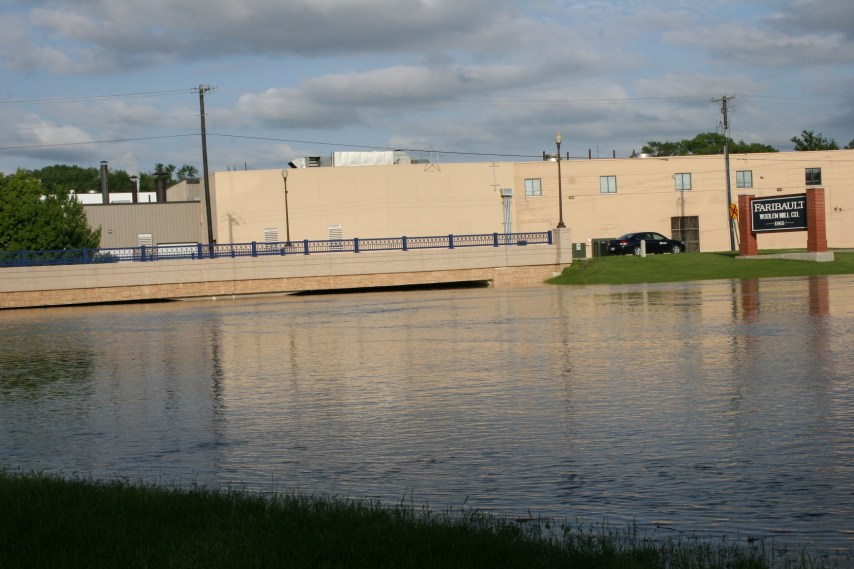 The rising Cannon River along Second Avenue nearly skims the bridge. Faribault Foods is in the background and the Faribault Woolen Mill is to the right.
