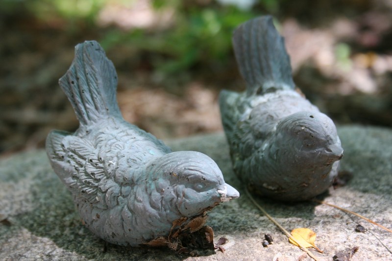 Bird art perched on a front yard rock.